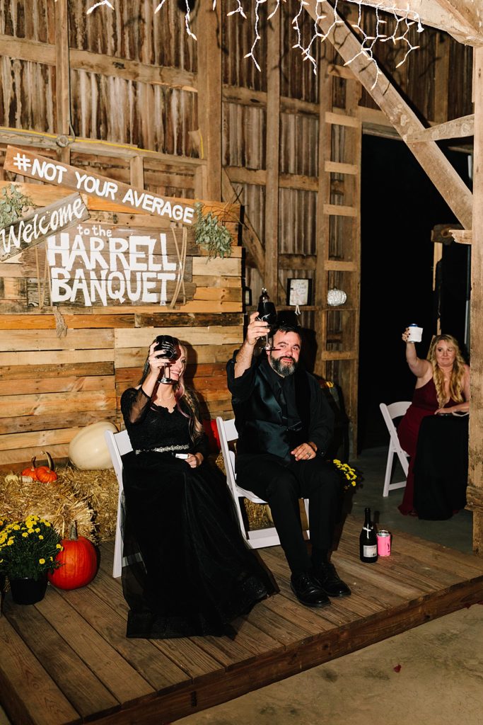 bride and groom toast during reception speeches at their halloween wedding with pumpkin decor