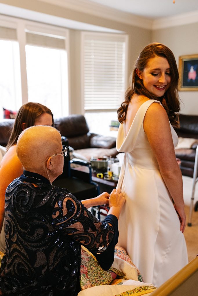 documentary wedding photography, mom zips up daughters wedding dress from her hospital bed, lulus backless dress, scoop back, cowl back, white dress, mom with breast cancer on daughters wedding day
