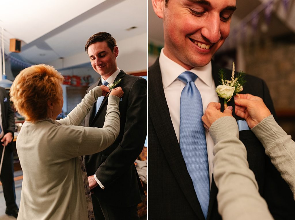 groom wearing a grey suit with blue tie, simple white rose boutonniere, at home wedding,