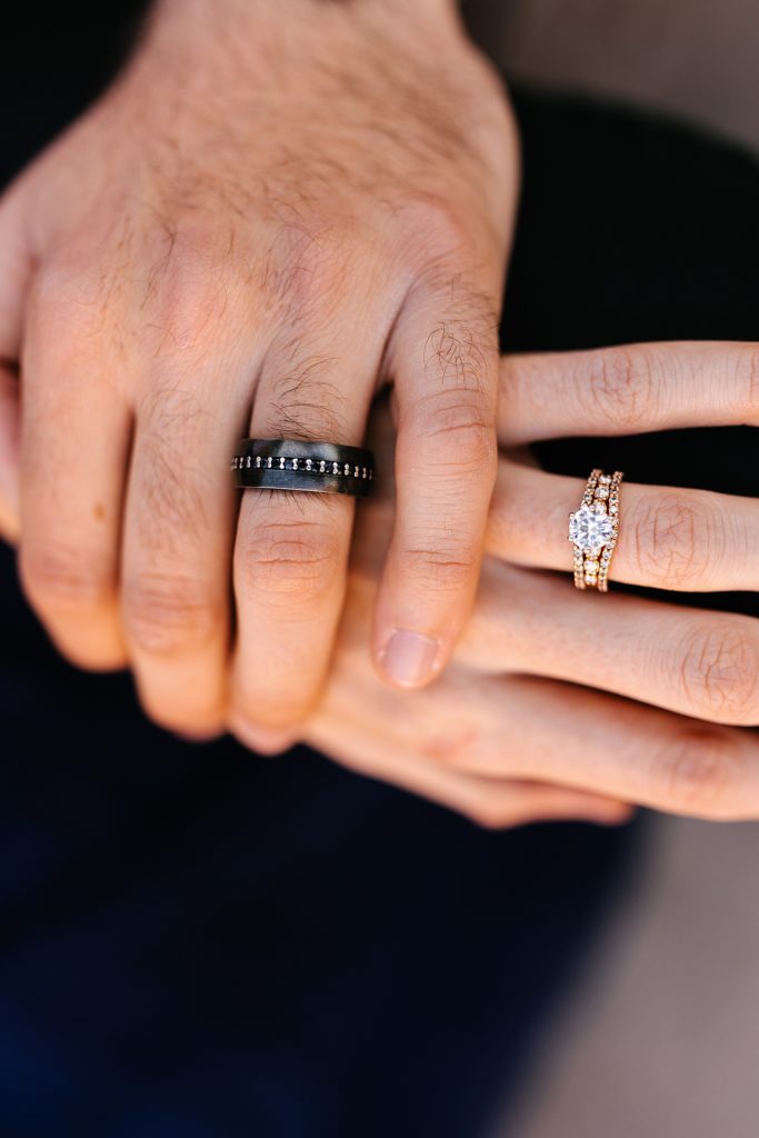 Up close image of man & woman's engagement rings on their fingers. 