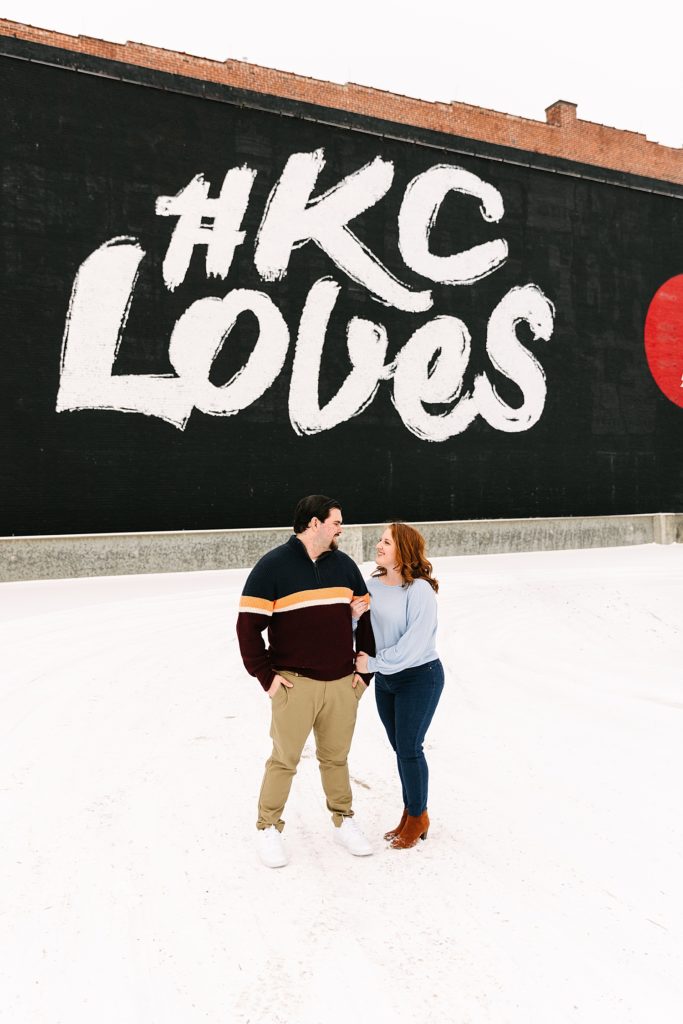 Couple looking at each other lovingly in front of the KC Love Mural.