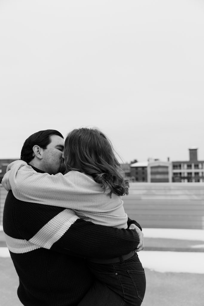 Black and white image of a man and woman kissing at their urban engagement session. 