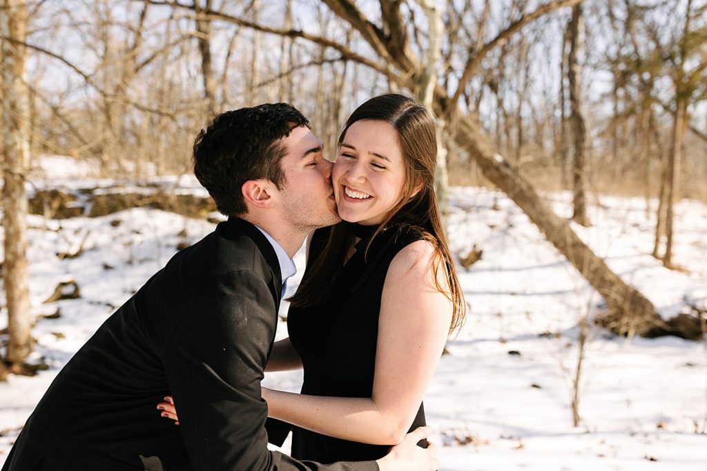 Man kissing woman's cheek while she smiles.