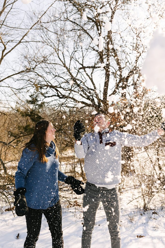 Man throwing up snow in the air with his fiancé. 