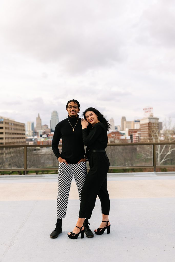 Portrait of a powerful man and woman posing on a rooftop with the city skyline behind them. 