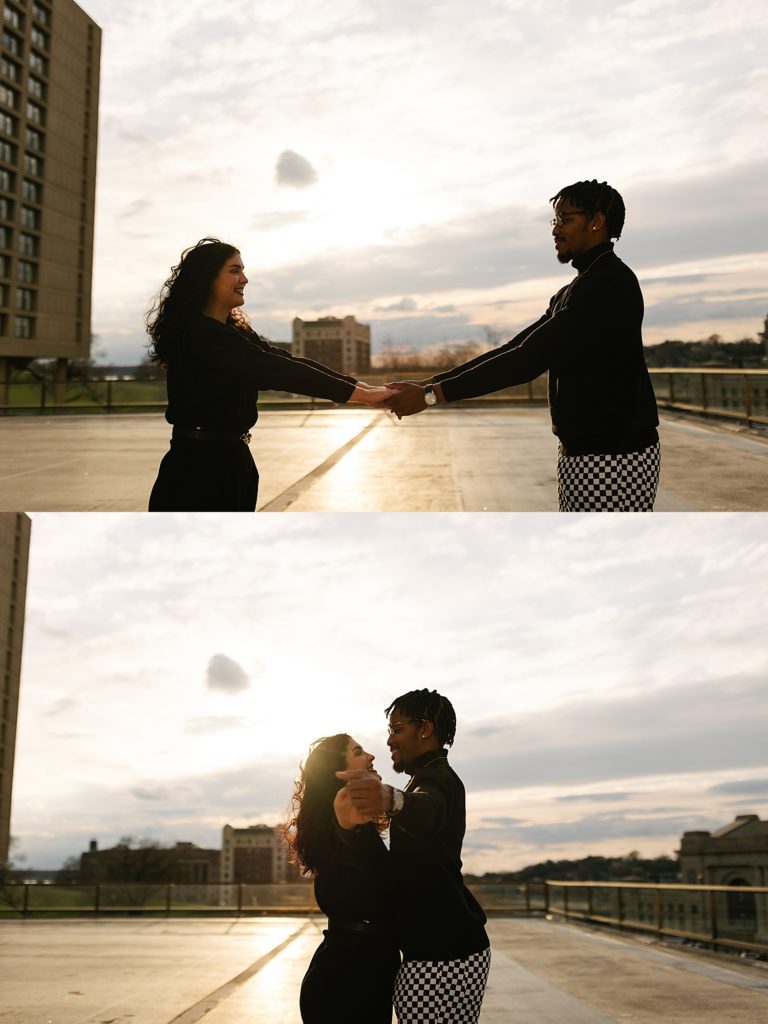 Engaged couple dancing on a rooftop with the sunset in the background.
