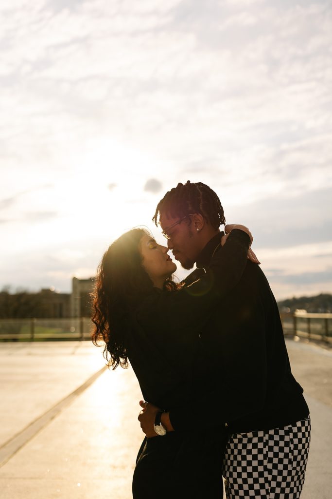 Man and woman about to kiss on a rooftop in the sunset light for their couples rooftop session.