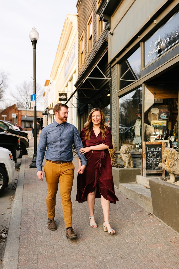 Woman and man in fall clothes walking down the street smiling.
