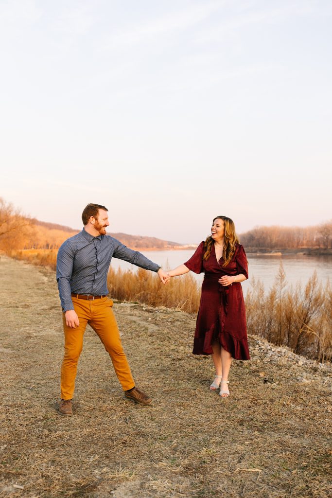 Man and woman in Fall colored clothing dancing next to a river. 