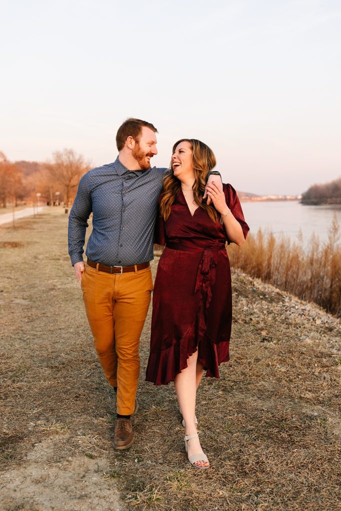 Man and woman in jewel toned clothes walking towards the camera next to a river. 