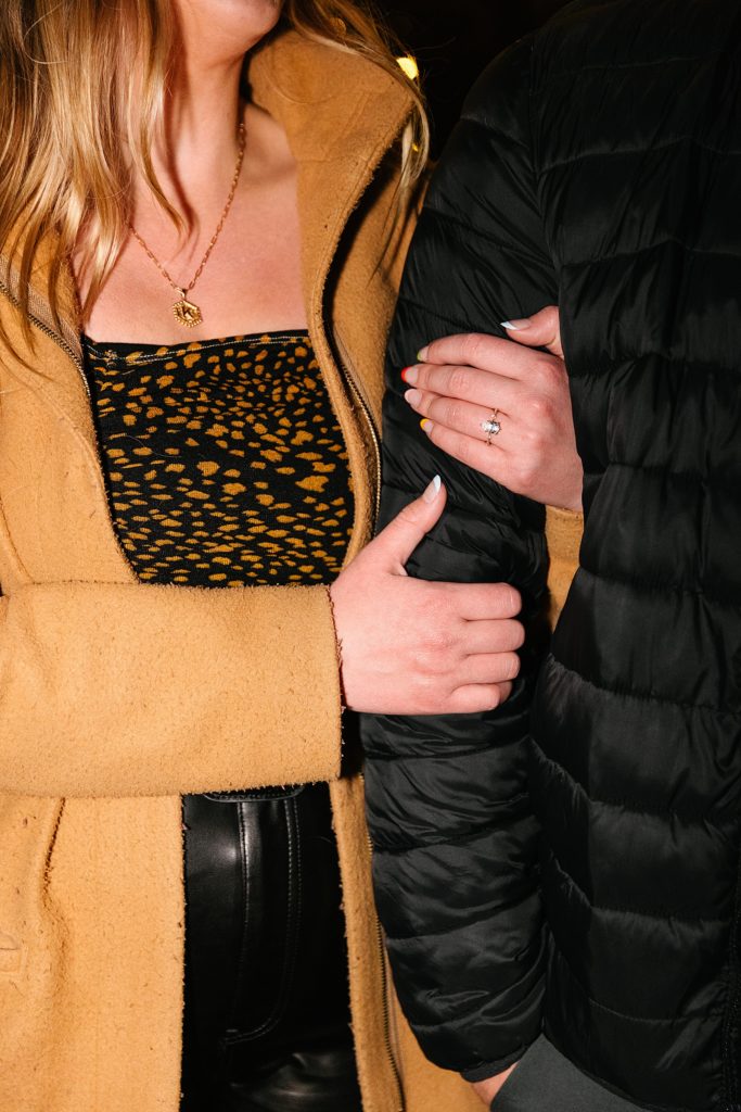 Woman holding mans arm with her new engagement ring in focus.