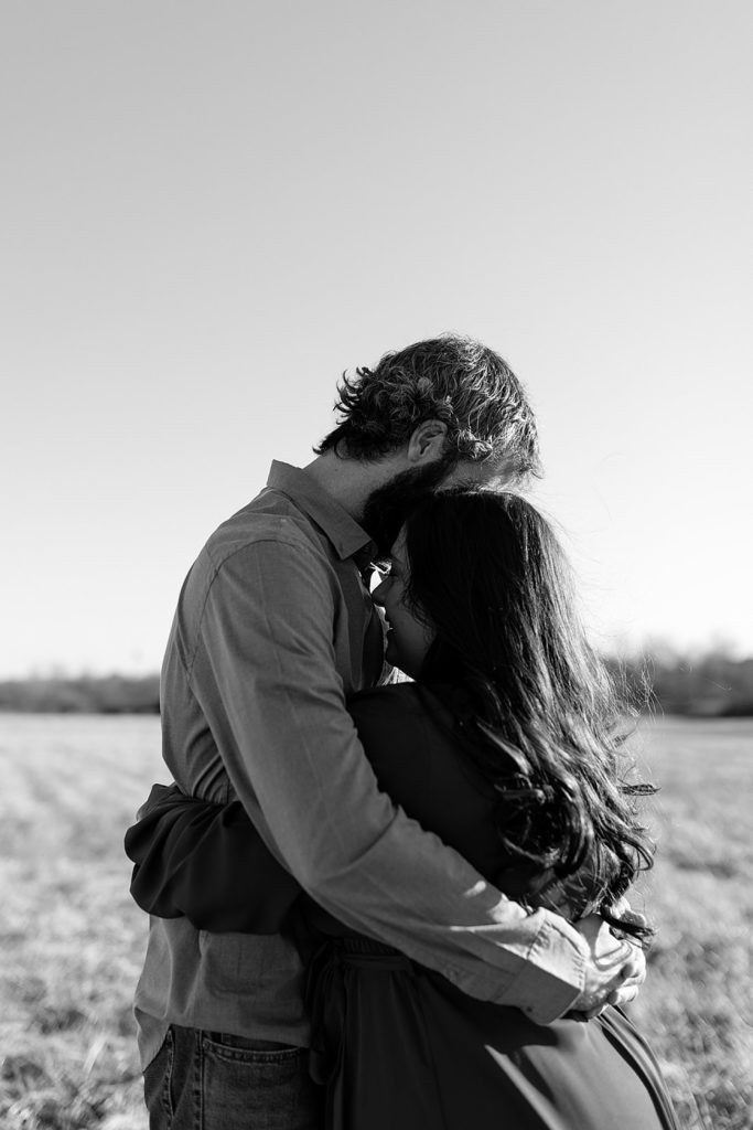 Black and white photo of a man and woman embracing outside. 