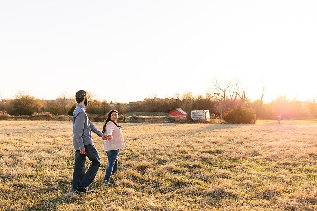 Engaged couple walking into the sunset on their farm land.