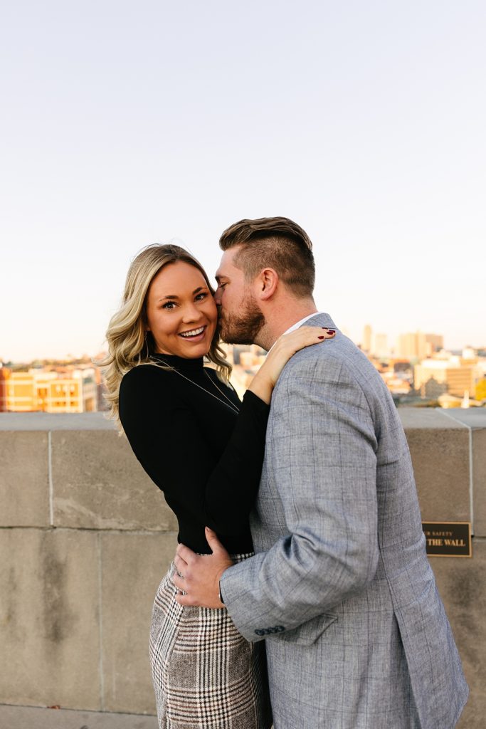 Man kissing his fiancé's cheek at their session with Kansas City Engagement Photographer. 