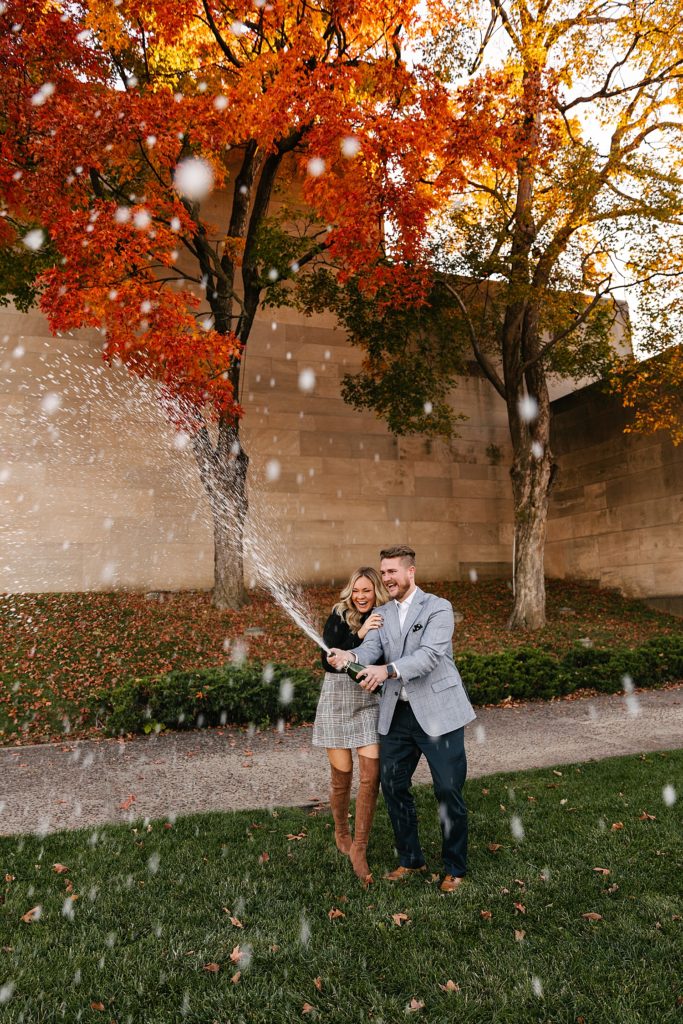 Engaged couple popping champagne at their session with Kansas City Photographer, Natalie Nichole.