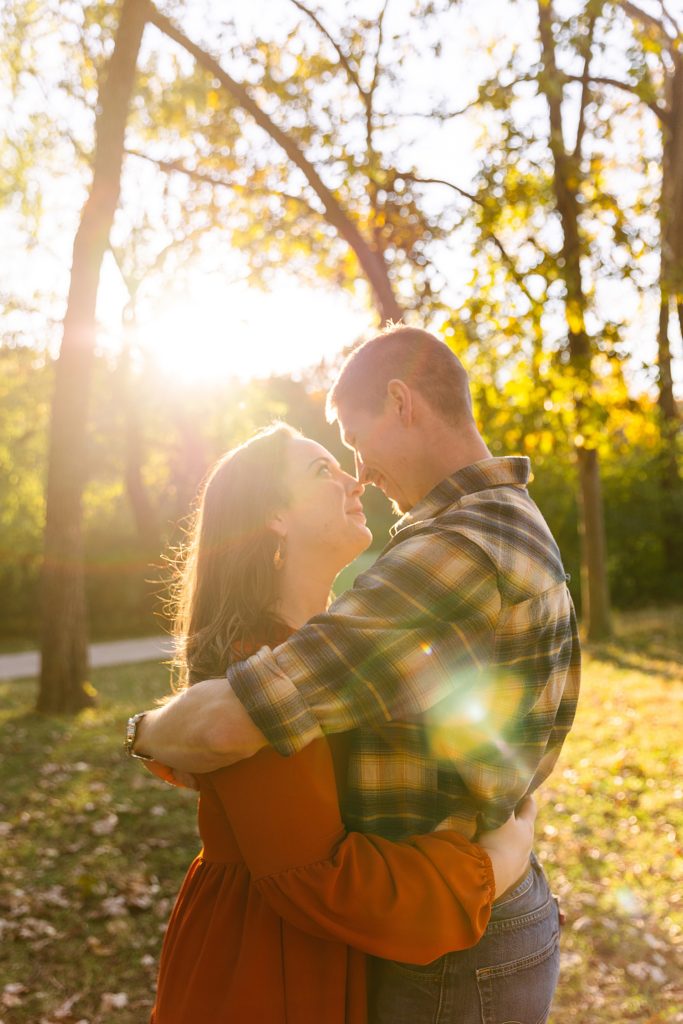 Woman and man embracing in the sunshine at Shawnee Mission Park for their golden hour shoot.