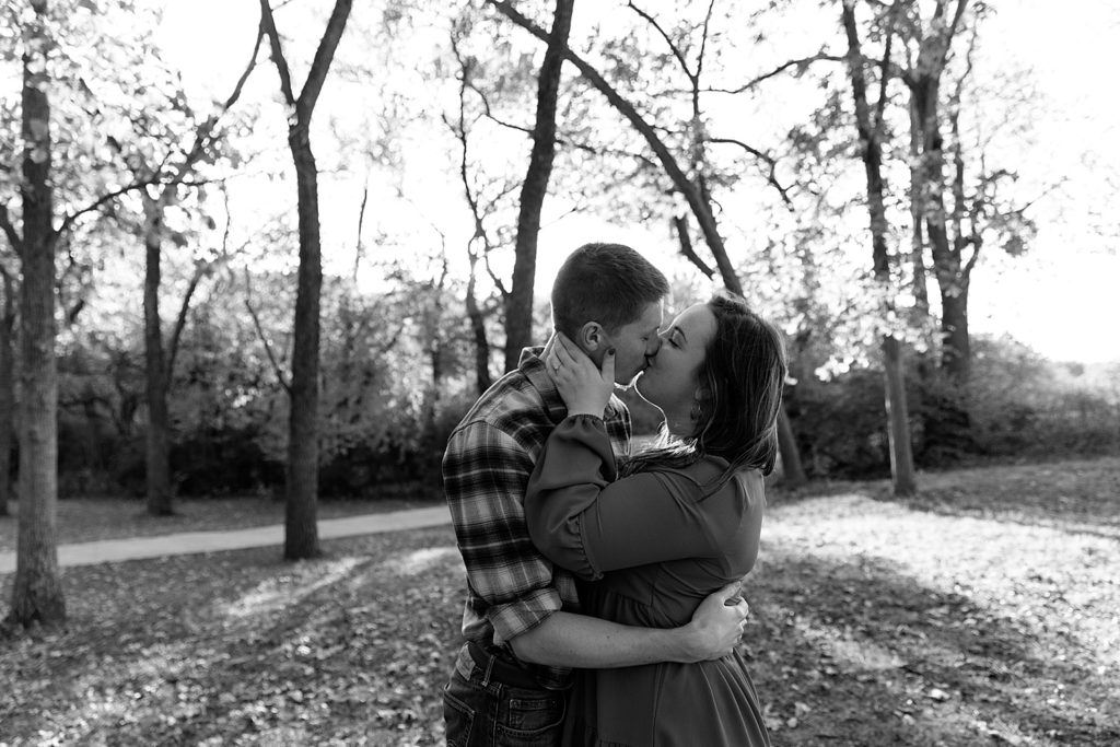 Engaged couple kissing in the trees at a KC park for their couples photo shoot. 