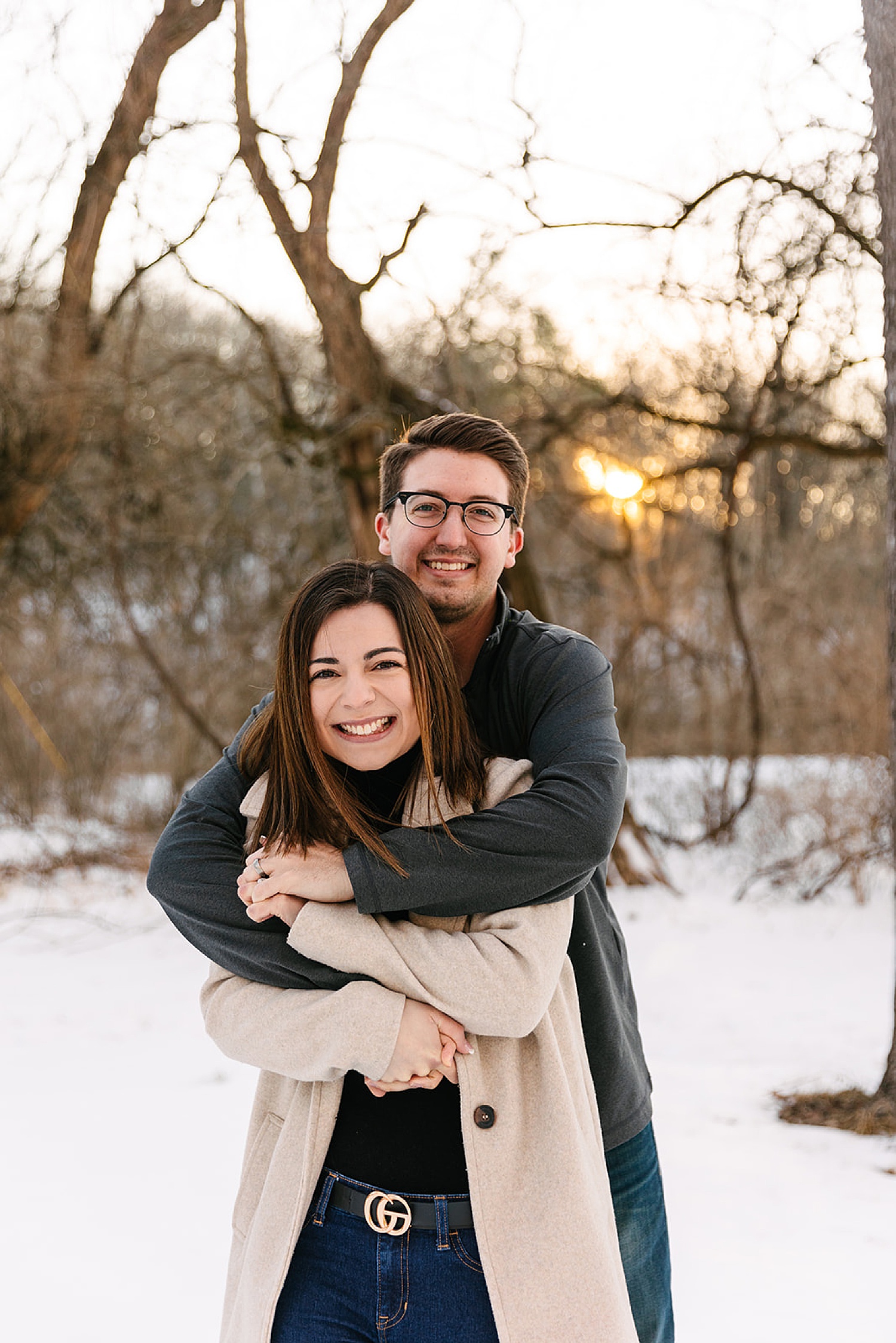 newly engaged couple smiling before golden hour in snowy park in Kansas City 