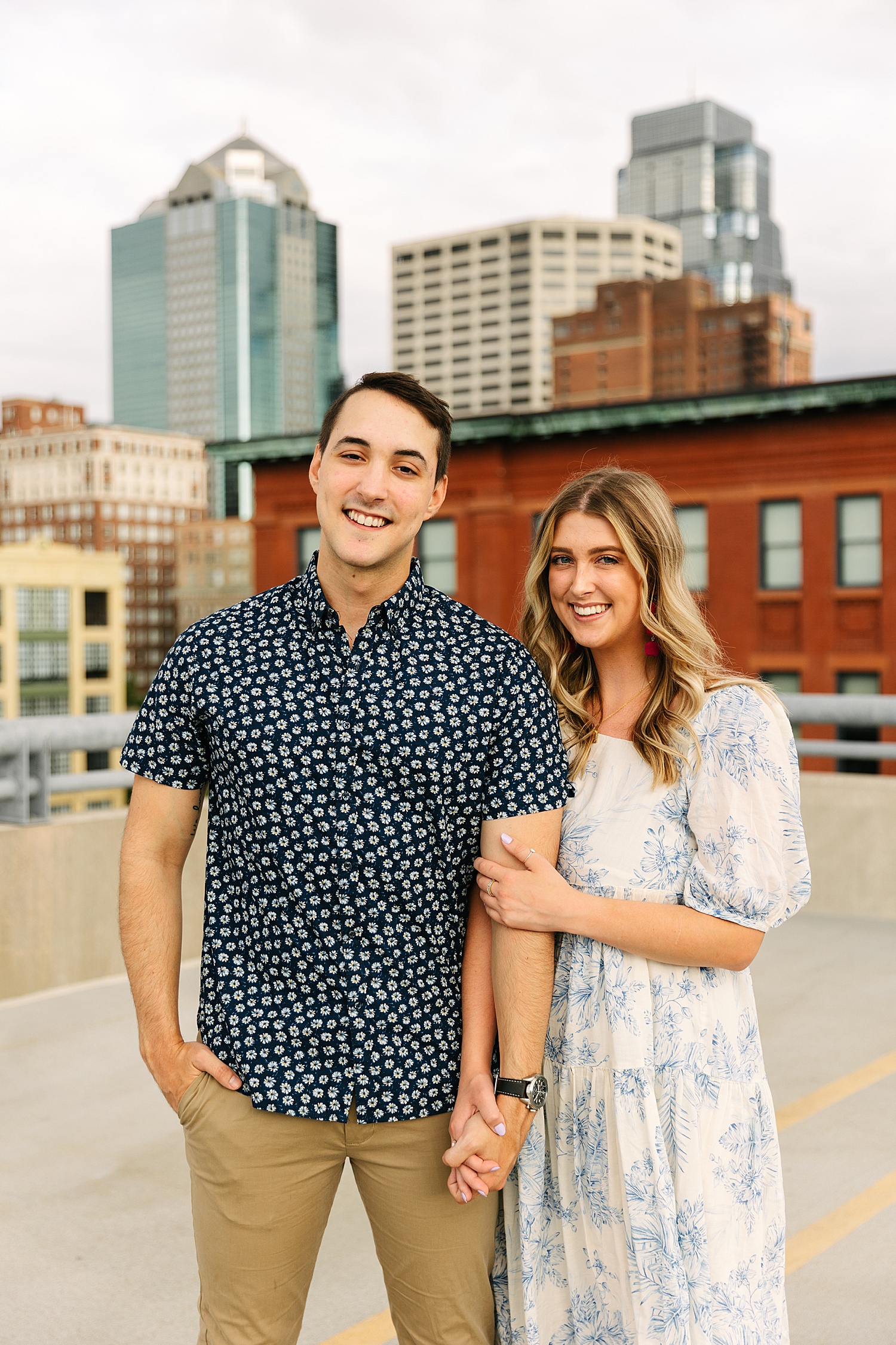 couple standing in front of Kansas City skyscraper on rooftop of parking garage