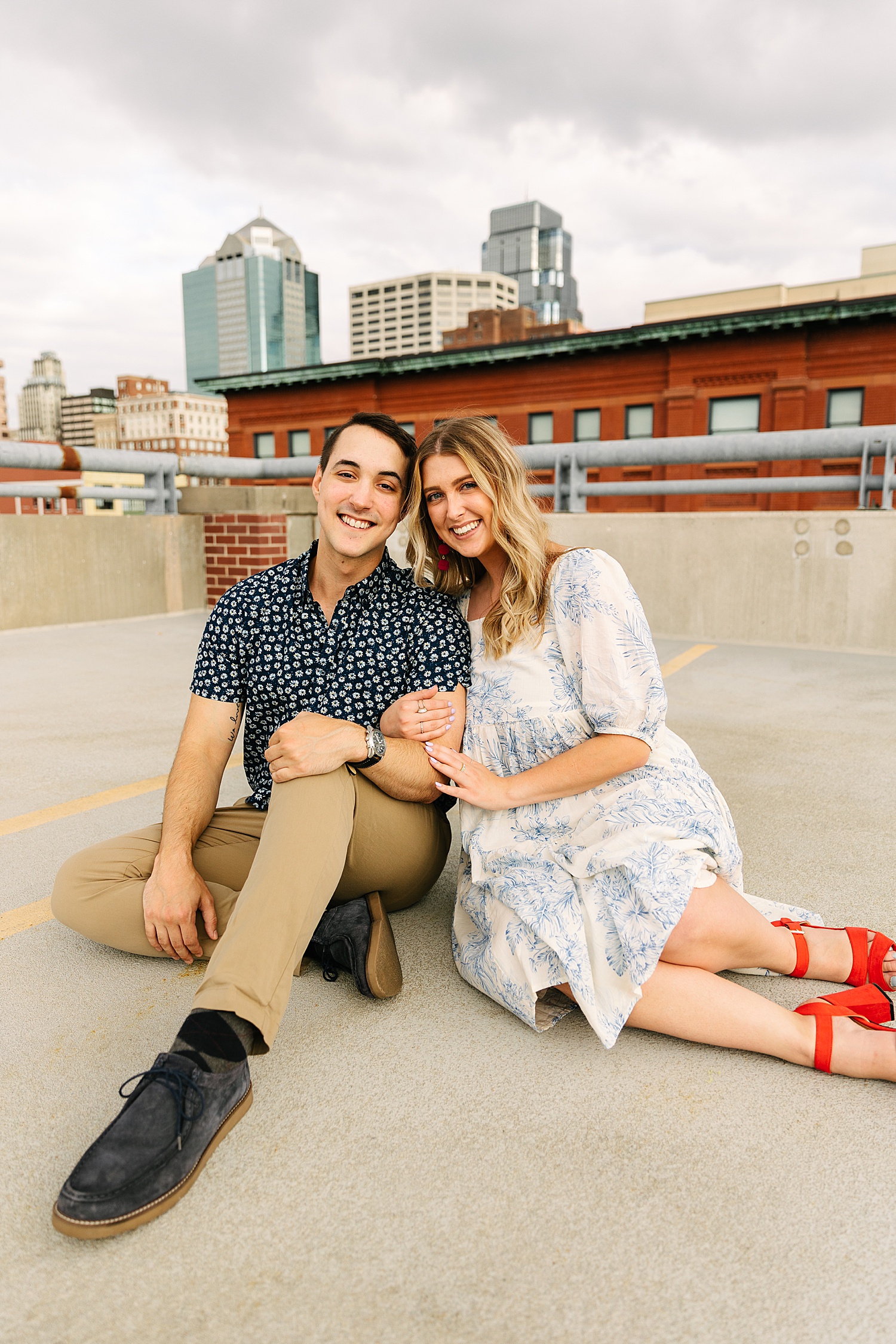 couple smiling on Kansas City rooftop wearing red heals and a long white dress