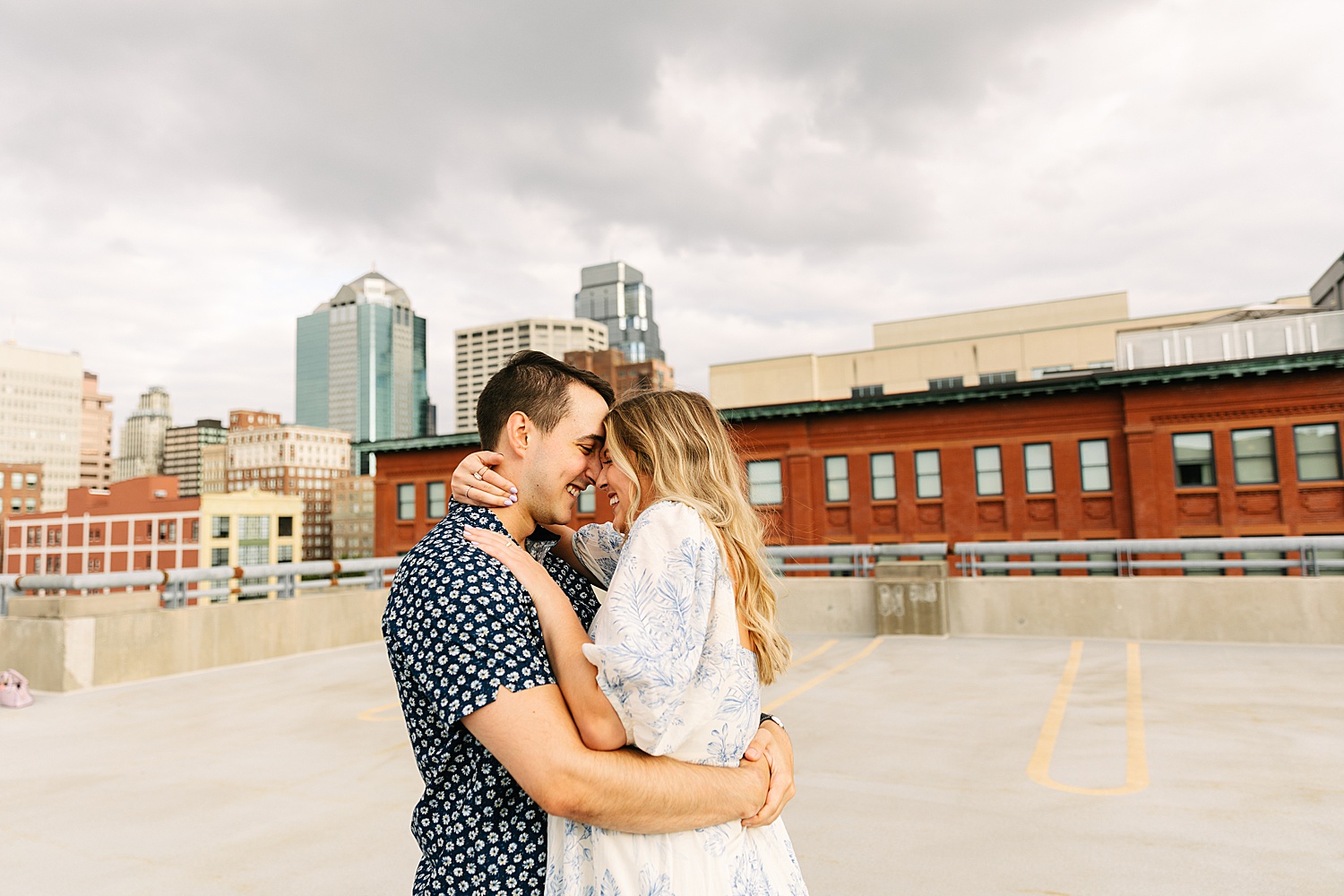engaged couples cuddles on rooftop with Kansas City photographer