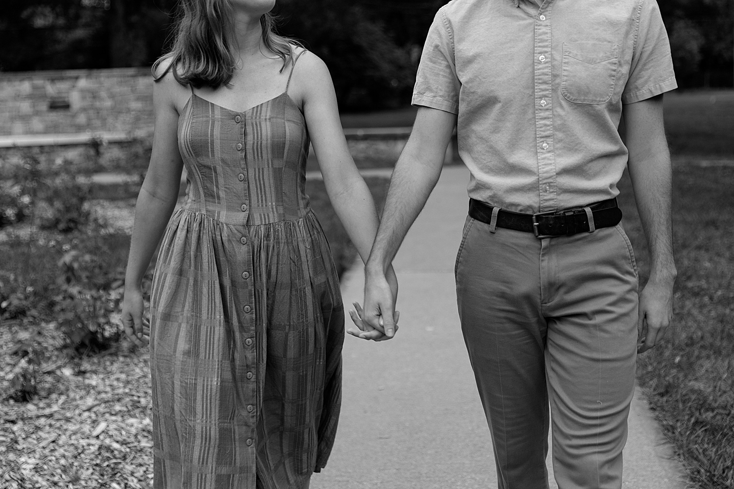 engaged couple holding hands walking the path at Kansas City park 