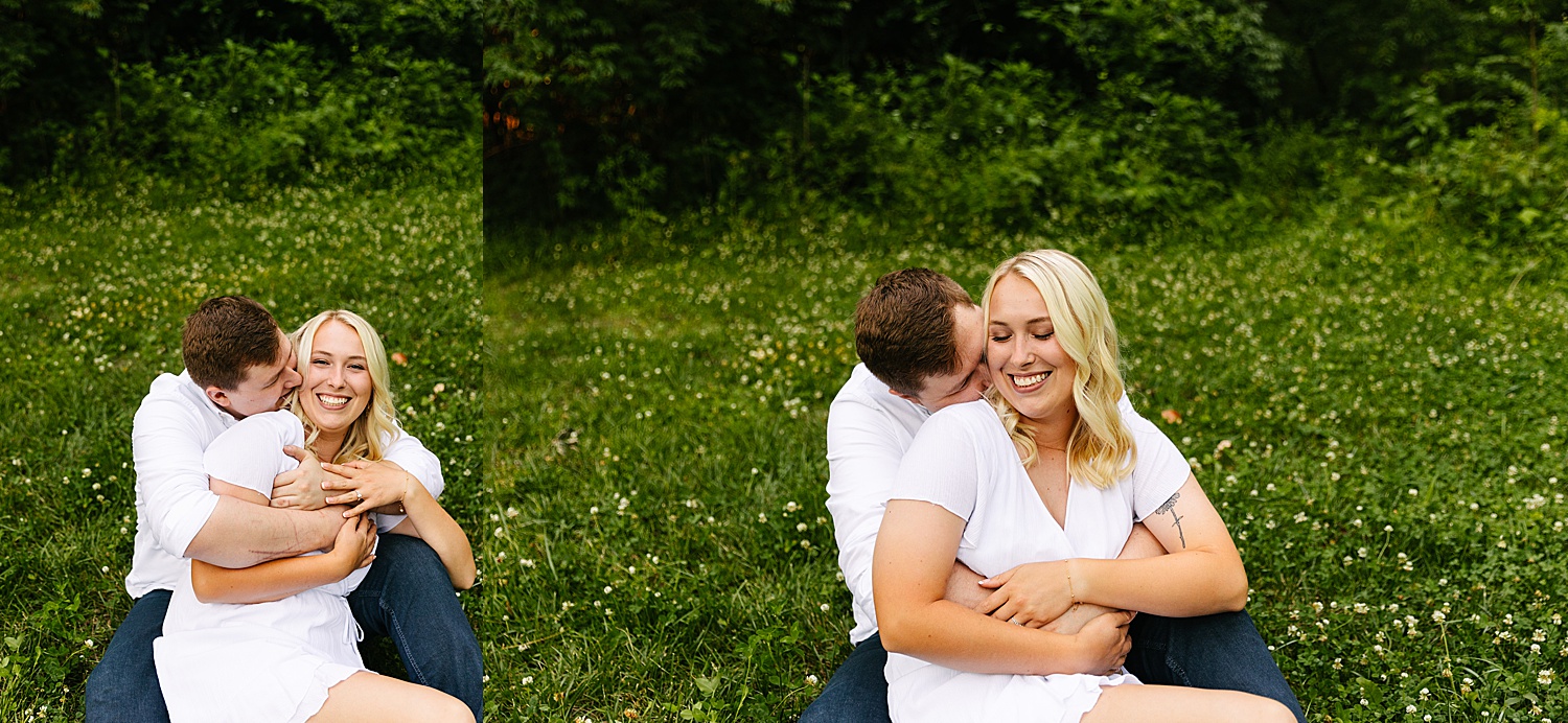 Newly engaged couple with tattoos holding each other sitting in a wildflower field